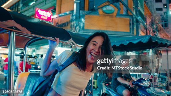 Young Asian woman tourist traveling by a Tuk Tuk vehicle on the street at Bangkok, Thailand. Holiday vacation trip. Young Asian woman tourist traveling by a Tuk Tuk vehicle on the street at Bangkok, Thailand. Holiday vacation trip.