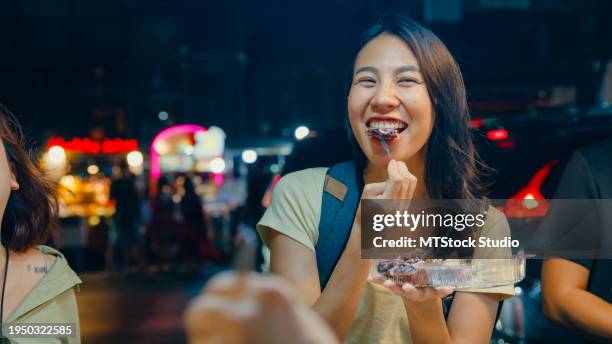 young asian female friends backpacker enjoy eating street food on the street at night market in bangkok, thailand. holiday vacation trip. - yaowarat road stock pictures, royalty-free photos & images