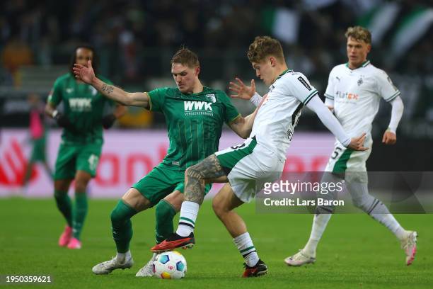 Philip Tietz of FC Augsburg is challenged by Luca Netz of Borussia Moenchengladbach during the Bundesliga match between Borussia Mönchengladbach and...