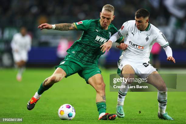 Philip Tietz of FC Augsburg is challenged by Joe Scally of Borussia Moenchengladbach during the Bundesliga match between Borussia Mönchengladbach and...