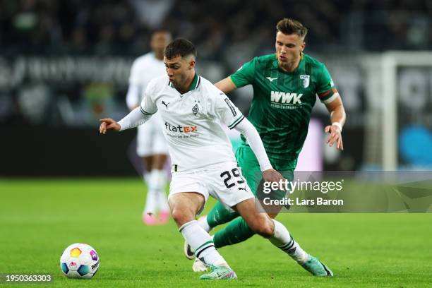 Joe Scally of Borussia Moenchengladbach challenged by Ermedin Demirovic of FC Augsburg during the Bundesliga match between Borussia Mönchengladbach...