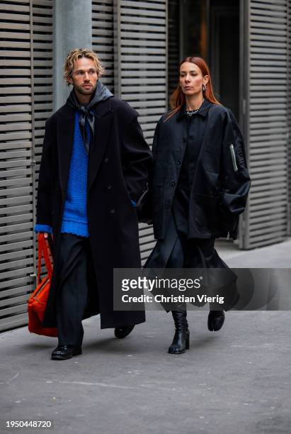 Couple Alice Barbier wears black bag, coat, boots & Sebastien Roques wears orange bag, black coat, blue knit outside Sacai during the Menswear...