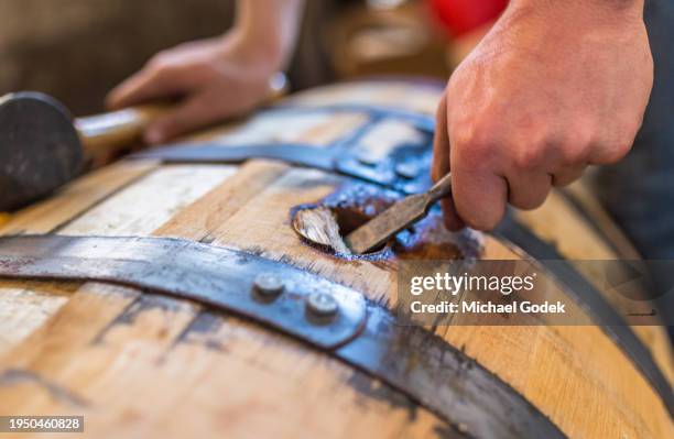 prying bung from whiskey barrel to dump and bottle - destillation stock-fotos und bilder