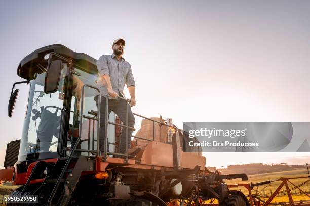 agricultor contemplando la vista desde arriba de la máquina agrícola - equipos agrícolas fotografías e imágenes de stock