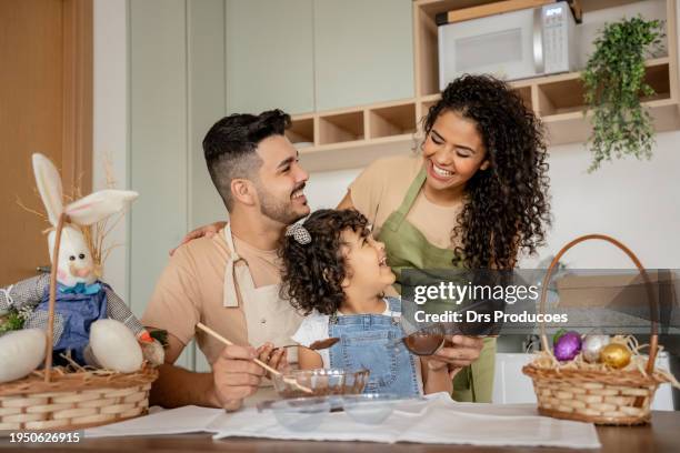 family with a daughter making chocolate for easter - couple chocolate stock-fotos und bilder