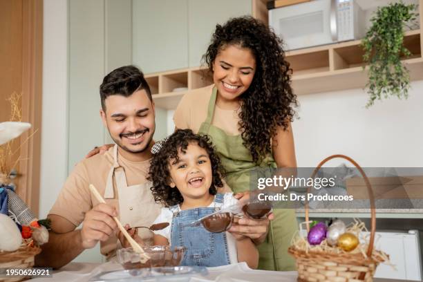 family with a daughter making chocolate for easter - easter decoration home stock pictures, royalty-free photos & images
