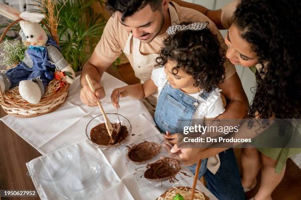 family with a daughter making chocolate for easter - couple chocolate stock-fotos und bilder