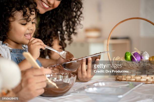 family with a daughter making chocolate for easter - child loves chocolates stock-fotos und bilder