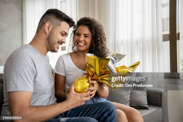 husband presenting his wife with an easter egg - couple chocolate - fotografias e filmes do acervo