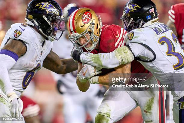 Christian McCaffrey of the San Francisco 49ers battles with Marcus Williams and Patrick Queen of the Baltimore Ravens in action during a game between...
