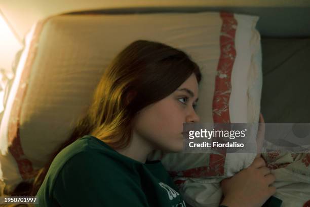 portrait of a teenage girl lying in bed - teenager girl blanket stockfoto's en -beelden