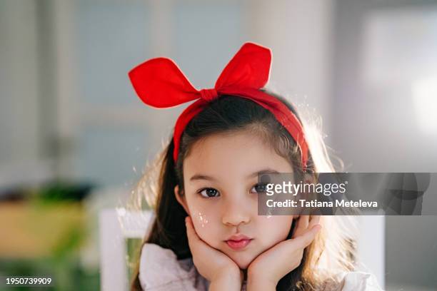 cute girl in headband, holding her face in hands and looking at camera: children's kawaii and cuteness - girls flashing camera 個照片及圖片檔