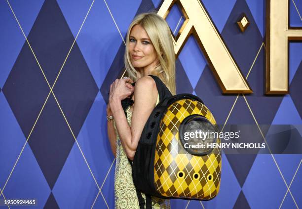 German model Claudia Schiffer holds a cat called 'Chip' in a backpack as she poses on the red carpet upon arrival to attend the world premiere of the...