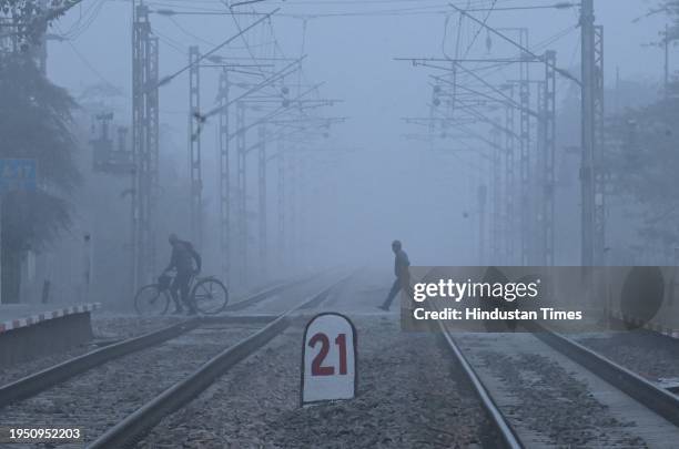 Commuters brave the early morning winter fog and chill as they cross Railway crossing in Dwarka in South West Delhi, on January 24, 2024 in New...