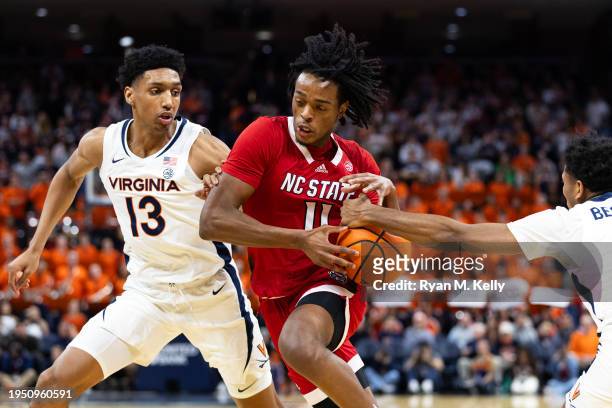 Dennis Parker, Jr. #11 of the NC State Wolfpack drives between Ryan Dunn and Reece Beekman of the Virginia Cavaliers in the first half during a game...