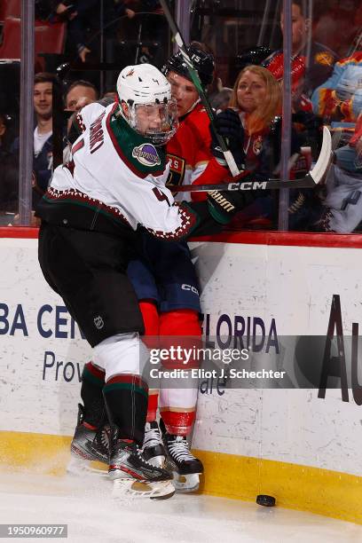 Juuso Valimaki of the Arizona Coyotes battles along the boards against Anton Lundell of the Florida Panthers at the Amerant Bank Arena on January 24,...