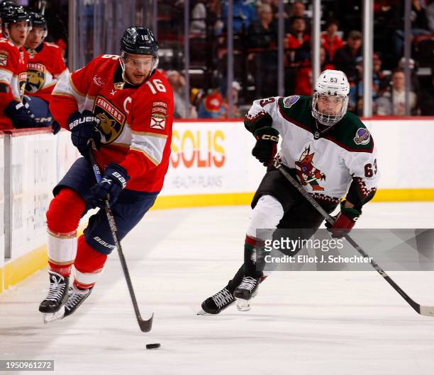 Aleksander Barkov of the Florida Panthers skates for possession against Matias Maccelli of the Arizona Coyotes at the Amerant Bank Arena on January...