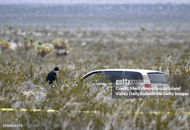 El Mirage, CA An Investigator with the San Bernardino County Sheriff's Department walks past one of two vehicles found in the high desert where 6...