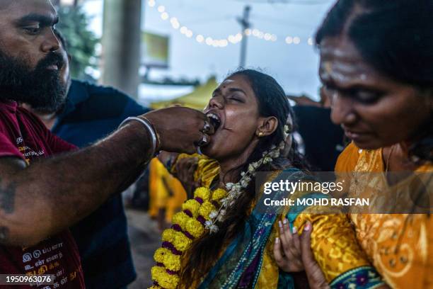 This picture taken on January 24, 2024 shows a Hindu devotee in a state of trance, with her tongue pierced with a steel skewer, before she makes her...