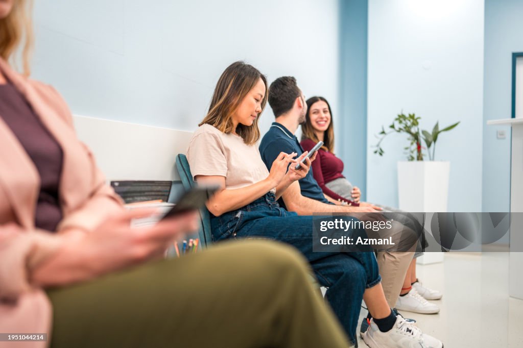 Mid Adult Asian Woman in Ultrasound Waiting Room Using Smartphone