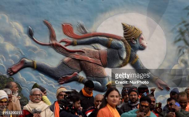 Devotees are standing in front of Lord Hanuman wall art on the day of the Ram temple consecration in Ayodhya, India, on January 22, 2024.