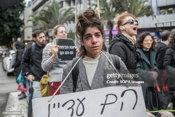 An Israeli woman with a placard that says "They are still alive" cries during a demonstration demanding an immediate hostage release and ceasefire of...