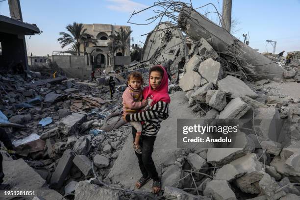 Palestinian girl holding a kid on rubble as people inspect destruction after an Israeli bombing of Omar bin Abdul-Aziz Mosque in Rafah, Gaza on...