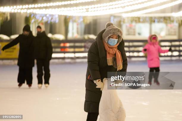 Girl wearing a medical mask seen skating at the "Big Ice Rink" in St. Petersburg. The "Big Ice Rink" is located in the central park of culture and...