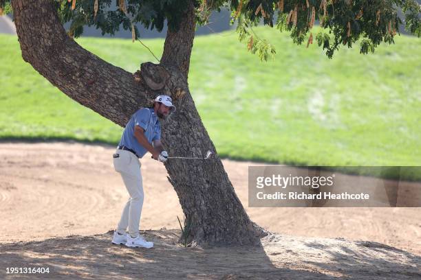 Cameron Young of the United States plays a shot left handed from under a tree on the 6th during the final round of the Hero Dubai Desert Classic at...