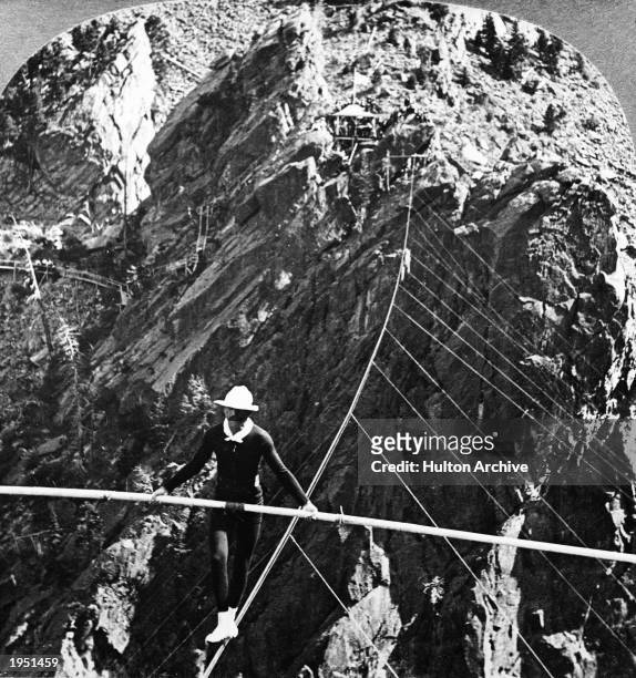 American daredevil and aviator William 'Ivy' Baldwin balances himself with a pole while crossing South Boulder Canyon, Eldorado Springs, Colorado,...