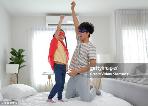 father and daughter on red dressed as superhero playing at home - superhero dad stock pictures, royalty-free photos & images