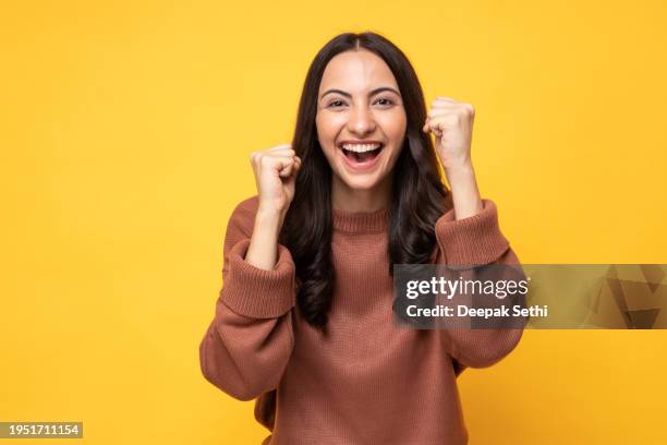 photo of young women in winter wear standing on yellow background stock photo - excitement stock pictures, royalty-free photos & images