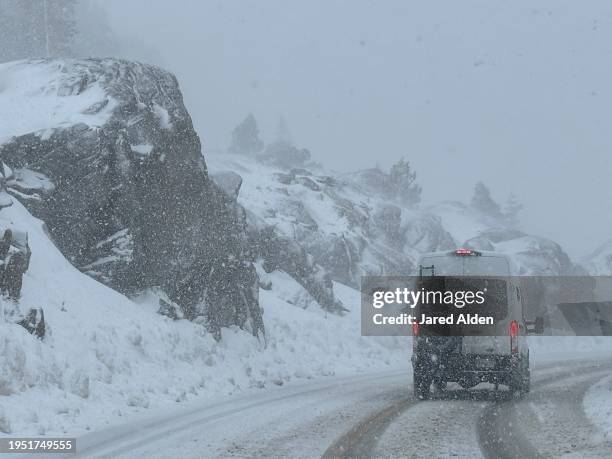 white van driving by rocks and granite cliffs in a snow storm on slippery snowy roads with snowflakes falling from the sky, donner pass road, donner summit, california - donner summit stock pictures, royalty-free photos & images