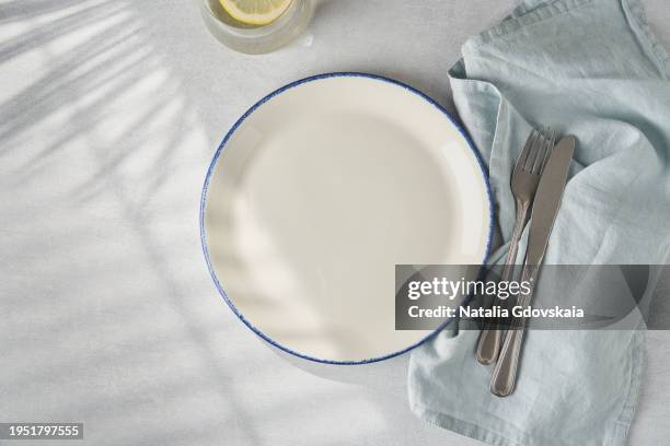 clean empty white plate, fork and knife on pastel grey table. concept for menu with utensil - tafelbesteck stock-fotos und bilder