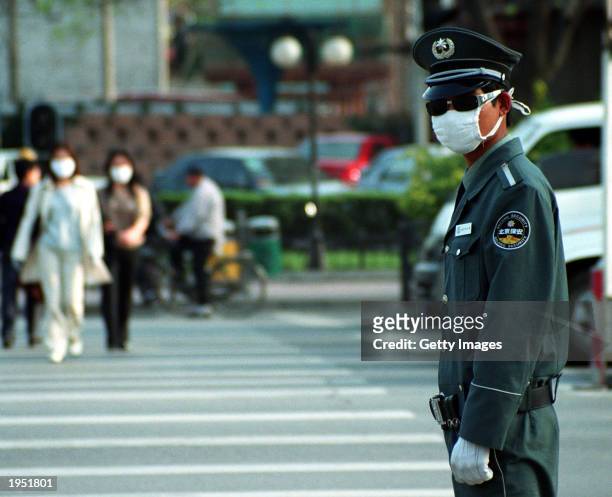 Traffic police officer on duty at an intersection in the Jianguomenwai district wears a face mask for protection from SARS April 25,2003 in Beijing,...