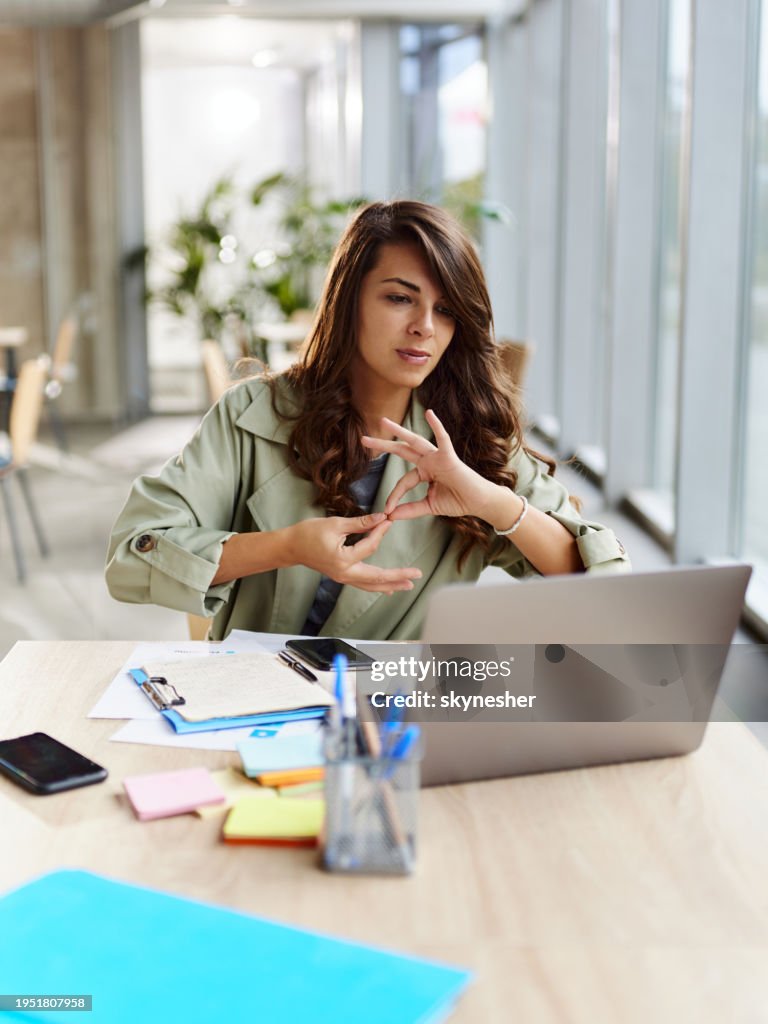 Deaf businesswoman having a video call over laptop in the office.
