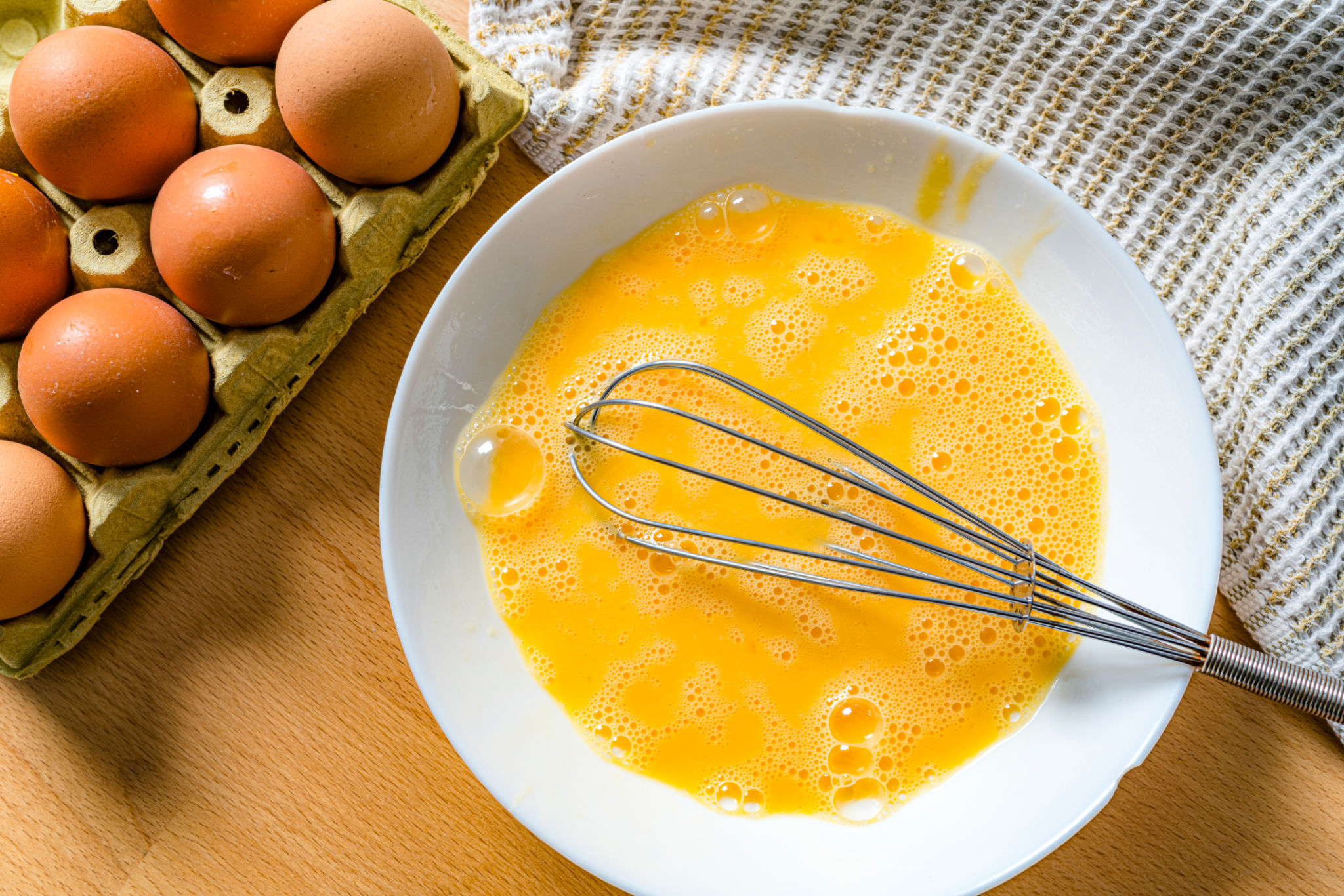 Overhead shot of scrambled raw eggs in a white bowl Overhead shot of scrambled raw eggs in a white bowl