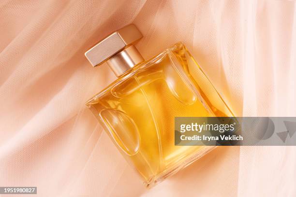 make-up cosmetic product for a woman  glass bottle perfume in a glass transparent bottle on gorgeous flowy tutu tulle nylon skirt in natural pastel pink beige peach color. - perfume stock pictures, royalty-free photos & images