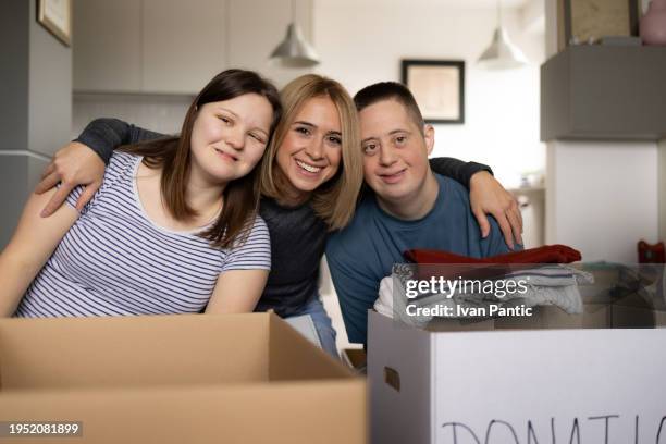 happy donation manager with her friends with special needs at home. - man holding donation box stock pictures, royalty-free photos & images