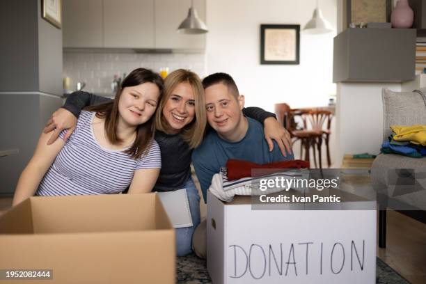 happy people with down syndrome and their donation manager at home. - man holding donation box stock pictures, royalty-free photos & images
