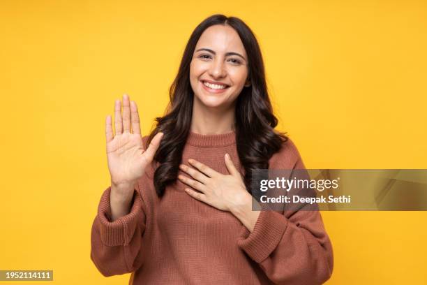 photo of young women in winter wear standing on yellow background stock photo - truehearts stock pictures, royalty-free photos & images