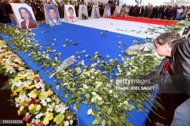 Une femme dépose une rose devant les portraits des huit élus de Nanterre tués la semaine dernière par Richard Durn, posés sur un drapeau français au...