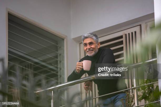 happy senior man contemplating in balcony - balcony stock pictures, royalty-free photos & images