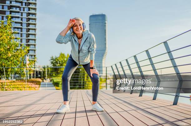 mature woman catching her breath after jogging - sport determination stock pictures, royalty-free photos & images