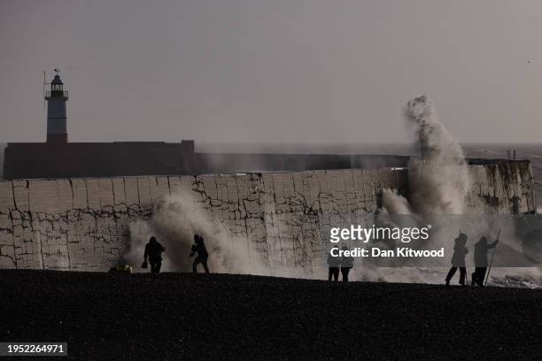 Geography students take beach surveys as waves strike a breakwater, with the Newhaven Lighthouse in the background, on January 22, 2024 in Newhaven,...