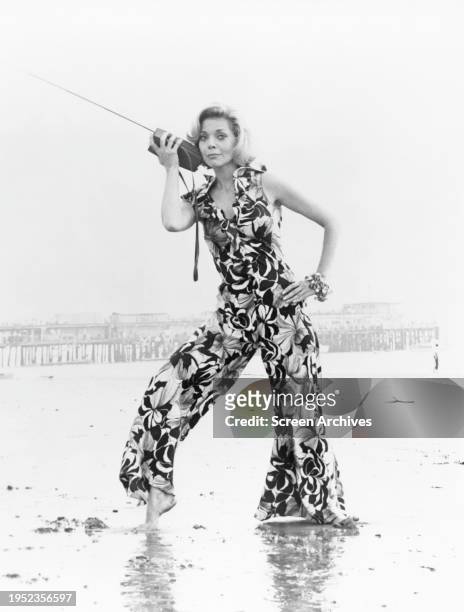 Barbara Bain barefoot on beach wearing sleeveless jumpsuit in a 1972 publicity .