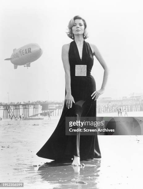 Barbara Bain in glamorous outfit with Goodyear Blimp in sky 1972.