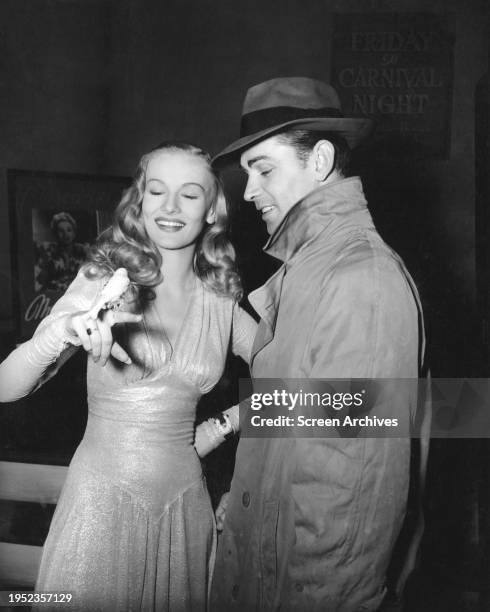 Alan Ladd and Veronica Lake holding bird on set of the 1942 film noir 'This Gun For Hire'.