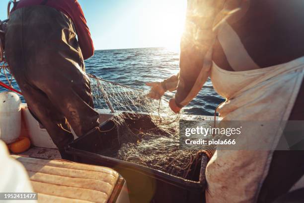 fisherman at work with net on trawler fishing boat - fischerboot stock-fotos und bilder