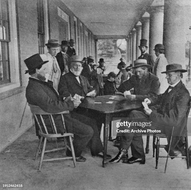 American shipping and railroad magnate Cornelius Vanderbilt playing cards with a group of men sitting around a table in Saratoga Springs, New York,...